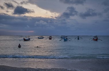 Kuta 'daki Pantai Jerman (Alman Sahili), Bali Endonezya' da günbatımı. Okyanusta kayıkları gösteren bir çekim.