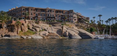 Aswan, Mısır 'da Nil nehri öğleden sonra, Sofitel Efsanesi Eski Katarakt Aswan ile nehirde erkek ve tekneleri gösteren bir çekim.