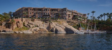 Aswan, Mısır 'da Nil nehri öğleden sonra, Sofitel Efsanesi Eski Katarakt Aswan ile nehirde erkek ve tekneleri gösteren bir çekim.