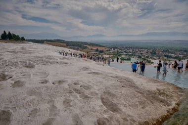 Pamukkale, Denizli Türkiye-7 Eylül 2023: Pamukkale Travertines of Pamukkale, çevresi beyaz kireçtaşıyla çevrili bir doğal termal havuz, sert kayaların üzerinden geçişle ulaşılıyor.