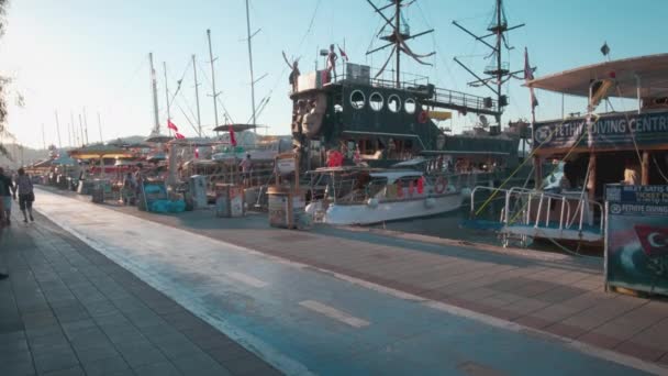 フェティエ トルコ 2023 レストランとマリーナにドッキングボートを示すフェティエの古いマリーナデイライトビュー カフェや遊歩道を歩く人々 — ストック動画