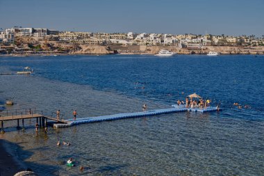 Sharm El Sheikh, Mısır 'daki Sharks Körfezi' nin panoramik görüntüsü, arka planda turistler, yatlar ve otellerle kızıl denizi gösteriyor.
