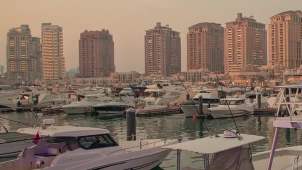 真珠のポルトアラビアマリーナ ドーハ カタールの日没ショットは バックグラウンドの人々とマリーナにドッキングされた豪華なヨットやボートを示しています — ストック動画