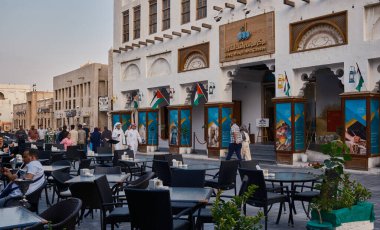Doha, Katar-6 Aralık 2023: Souq Waqif ana caddesi öğleden sonra çekimleri Souq Waqif sanat merkezi, restoranlar, yürüyen insanlar ve Katar bayrağını gösteriyor 