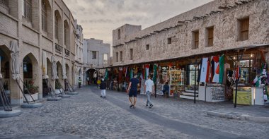 Souq Waqif, Doha, Katar ana caddesinde 2023 AFC Asya kupası sırasında geleneksel Arap Tekstil Dükkanı, Kafe, yerli ve ziyaretçilerin yürüyüşünü gösteriyor.. 