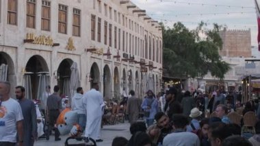 Doha, Katar-6 Aralık 2025: Souq Waqif Main caddesi öğleden sonra çekimleri geleneksel antika dükkanları, kahve dükkanları, yürüyen insanlar ve Katar bayrağını gösteriyor
