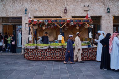 Doha, Katar - 3 Mart 2024: Souq Waqif Main caddesi öğleden sonra, geleneksel Arap Tekstil Dükkanı, Kafeler, yerliler ve yürüyen ziyaretçileri gösteren bir çekim. 