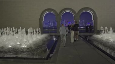 Doha, Katar - 29 Ağustos 2020: Doha ufuk çizgisi günbatımı, İslam Sanatları Müzesi 'nden turistlerin ön planda fotoğraf ve fıskiyelerle çekilmiştir.