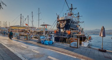 Fethiye 'deki Fethiye eski marinası, Mula, Türkiye gündüz görüşü marinada restoran, kafe ve gezinti alanında yürüyen insanları gösteren tekneler görülüyor.