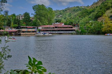 Sera Gl lake (Trabzon lake) in Trabzon, Turkey daylight view with people in boats and restaurants in background. clipart