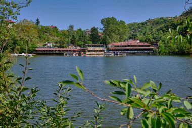 Trabzon 'daki Sera Gl Gölü (Trabzon Gölü), Türkiye' nin gündüz görüşü ve arka plandaki tekne ve restoranlarda insanlar.