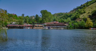 Trabzon 'daki Sera Gl Gölü (Trabzon Gölü), Türkiye' nin gündüz görüşü ve arka plandaki tekne ve restoranlarda insanlar.