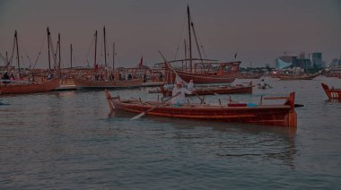 Katara14. Katar geleneksel dhow festivali Doha Katar Güneş Şutu Katılımcı ülkelerin bayrakları ve siluetleri ile Arap Körfezi 'nde geleneksel dhowları gösteriyor