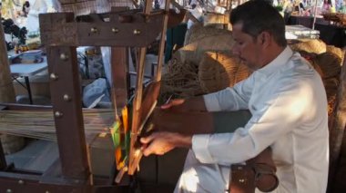 Doha, Katar - 6 Aralık 2024: Katara 14. Geleneksel Dhow Festivali sırasında geleneksel ahşap dokuma tezgahı ören Arap bir zanaatkar