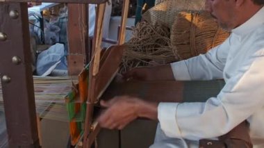 Doha, Katar - 6 Aralık 2024: Katara 14. Geleneksel Dhow Festivali sırasında geleneksel ahşap dokuma tezgahı ören Arap bir zanaatkar