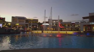 Kahire, Mısır - 28 Aralık 2023: Kahire festivali alışveriş merkezi yemek salonu gece manzarası fıskiyeleri, restoranlar, kahve dükkanları, arka planda insanlar ve bulutlar görünüyor