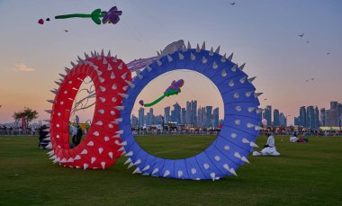Qatar Kite Festivali 2025 Eski Doha Limanı 'nda (Mina Bölgesi) gün batımı çekimleri Doha ufkunda süzülen renkli uçurtmaların muhteşem gösterisini gösteriyor.