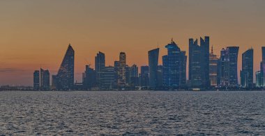 Doha, Katar-21 Mart 2025: Doha Katar alacakaranlıkta Corniche caddesinden ufuk çizgisi ve Arap körfezinde eşarplar