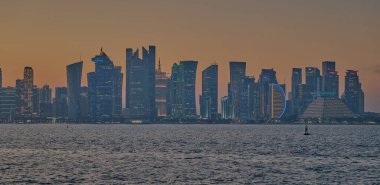 Doha, Katar-21 Mart 2025: Doha Katar alacakaranlıkta Corniche caddesinden ufuk çizgisi ve Arap körfezinde eşarplar