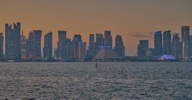 Doha, Katar-21 Mart 2025: Doha Katar alacakaranlıkta Corniche caddesinden ufuk çizgisi ve Arap körfezinde eşarplar