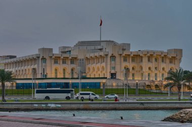 Doha, Katar-25 Nisan 2025: Corniche gezinti günbatımında Katar bayrağı ve arabalarla çekilen Amiri Diwan