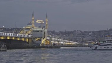 İstanbul, Türkiye - 9 Nisan 2025: İstanbul 'un Eminn çeyreği, Türkiye Yeni Cami ve Galata Köprüsü' nü gösteren feribottan gün batımı.