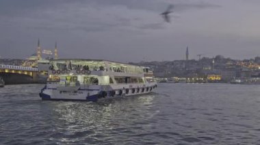İstanbul, Türkiye - 9 Nisan 2025: İstanbul 'un Eminn çeyreği, Türkiye Yeni Cami ve Galata Köprüsü' nü gösteren feribottan gün batımı.