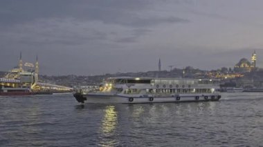 İstanbul, Türkiye - 9 Nisan 2025: İstanbul 'un Eminn çeyreği, Türkiye Yeni Cami ve Galata Köprüsü' nü gösteren feribottan gün batımı.