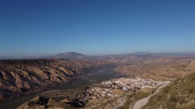 Gorafe, Desierto de los colaos 'taki kuru vadi ve dağların hava aracı görüntüsü. Mavi gökyüzü, Sierra Nevada, Granada, İspanya. Endülüs 'teki bitkilerle kaplı İspanyol çöl kanyonu. Dağların üzerinden uçuyor