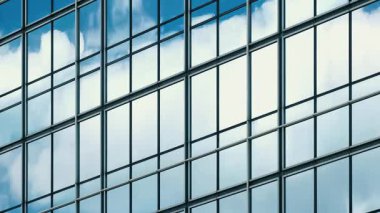 Mavi gökyüzünün zaman atlaması ve bulutların yapısal modüler cam duvara yansıması. 