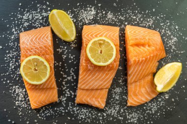 Koyu taştan bir arka planda baharatlı taze somon balığı bifteği. Tuz, baharat, baharat ve diğer malzemeler..