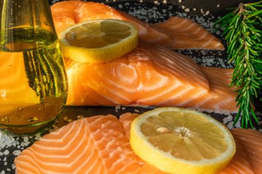 Koyu taştan bir arka planda baharatlı taze somon balığı bifteği. Tuz, baharat, baharat ve diğer malzemeler..