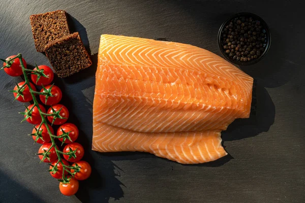 Koyu taştan bir arka planda baharatlı taze somon balığı bifteği. Tuz, baharat, baharat ve diğer malzemeler..