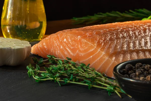 Koyu taştan bir arka planda baharatlı taze somon balığı bifteği. Tuz, baharat, baharat ve diğer malzemeler..