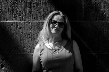 Beton bir duvarın arkasında kısa saçlı güzel bir kadının siyah beyaz portresi. Işık ve gölgenin oyunu.