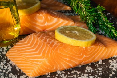 Koyu taştan bir arka planda baharatlı taze somon balığı bifteği. Tuz, baharat, baharat ve diğer malzemeler..