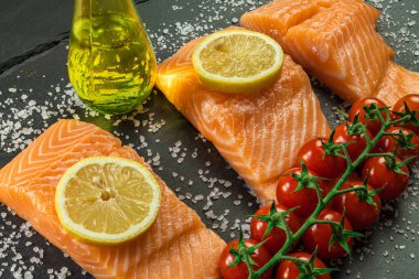 Koyu taştan bir arka planda baharatlı taze somon balığı bifteği. Tuz, baharat, baharat ve diğer malzemeler..