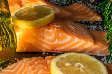 Koyu taştan bir arka planda baharatlı taze somon balığı bifteği. Tuz, baharat, baharat ve diğer malzemeler..