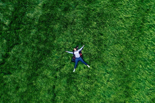 Parktaki büyük yeşil bir çayırda aşık bir kız. Mutluluk ve sükunetin drone görüntüsü.