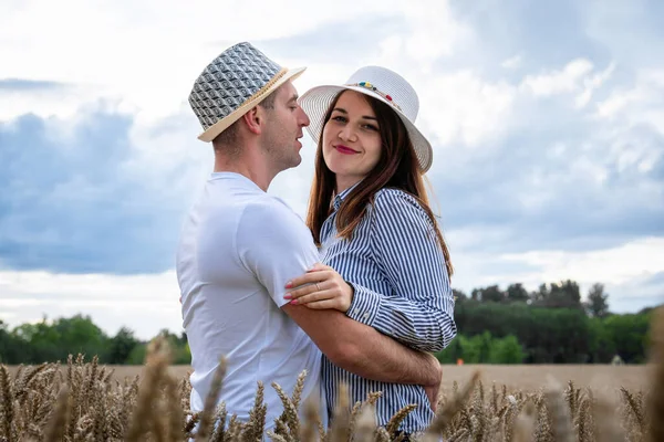 A couple in love enjoys relaxing in a wheat field. Romantic couple hugging in a moment of love in a golden wheat field. The concept of people, lifestyle, travel, nature and recreation.