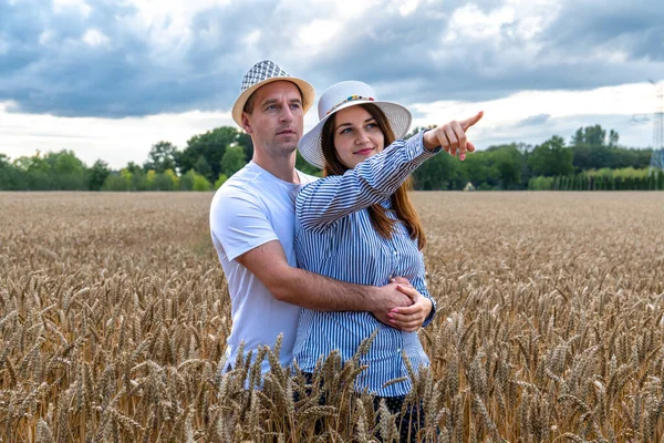 A couple in love enjoys relaxing in a wheat field. Romantic couple hugging in a moment of love in a golden wheat field. The concept of people, lifestyle, travel, nature and recreation.
