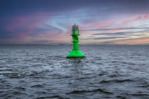 Буй, обозначающий границы водного пути. Ярко-зеленый буй, направляющий корабли в Северном море.