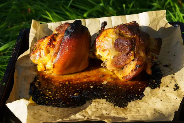 Parşömen kağıdında fırında pişirilmiş domuz budu. Doğada büyük miktarda yiyecek var. Yakın plan..