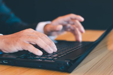 Ofis masasında dizüstü bilgisayarla çalışan bir iş adamı elleri.