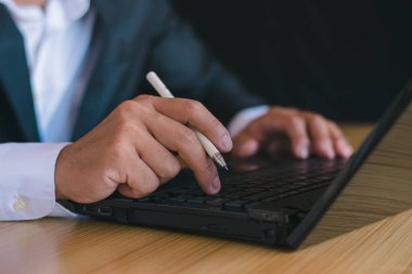 Not defteri bilgisayarıyla çalışan ve ofis masasına not almak için kalem kullanan işadamlarının yakın plan fotoğrafları.