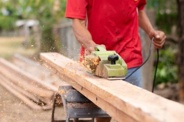 Bir ev inşaatçısı, mobilya yapmak ve ev onarımı için malzeme hazırlamak için bir uçak kullanıyor..