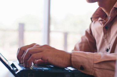 Ofis masasında dizüstü bilgisayarla çalışan erkek eller.