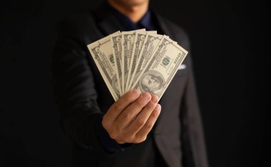 İş adamı Amerikan dolarlarını gösteriyor. Para kazanma kavramı, yatırım kararı, iş eğilimi.