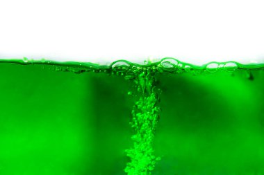 Beyaz arka planda köpüklü yeşil gazoz içeceği yakın plan çekimi.