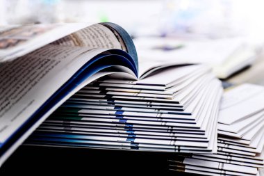 Açık kitap ve dergi yığınları belirli bir noktaya odaklanır Beyaz bir arkaplan, izole edilmiş